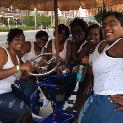 Group of women standing and sitting on party pedal bike
