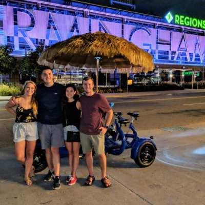 Small group of people standing in front of small party pedal bike