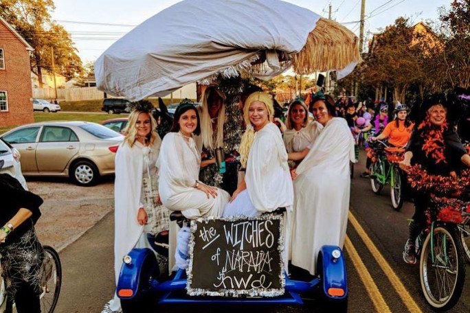 Group of women bike riders sitting on party pedal bike in Halloween costumes